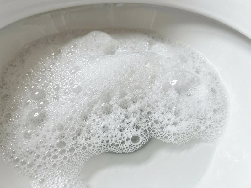 Macro close-up of dense expanding white foaming lather in toilet bowl